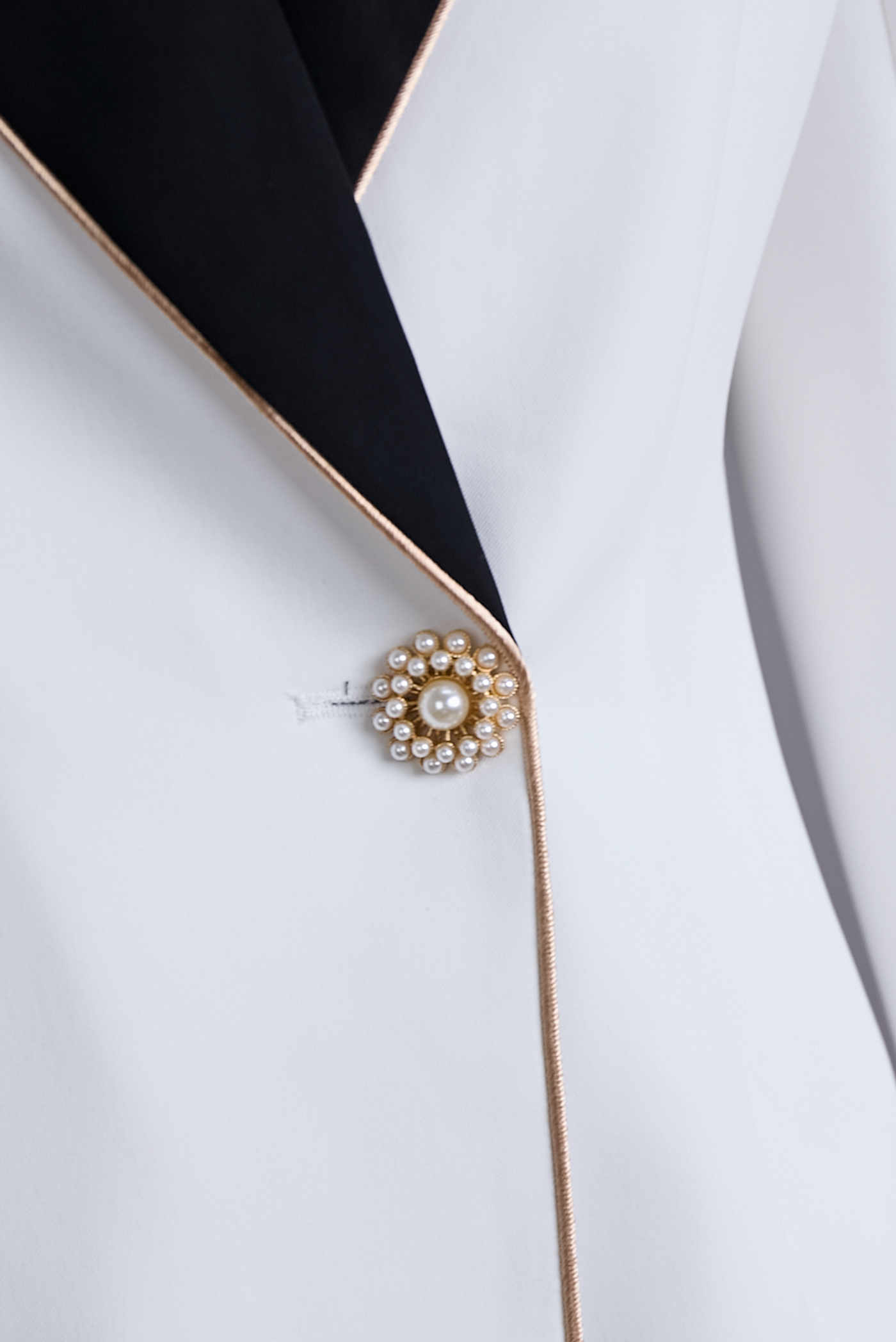 Elegant asymmetrisk hvid blazer med sorte kontrastreverser