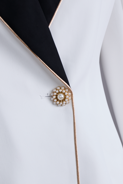 Elegant asymmetrisk hvid blazer med sorte kontrastreverser